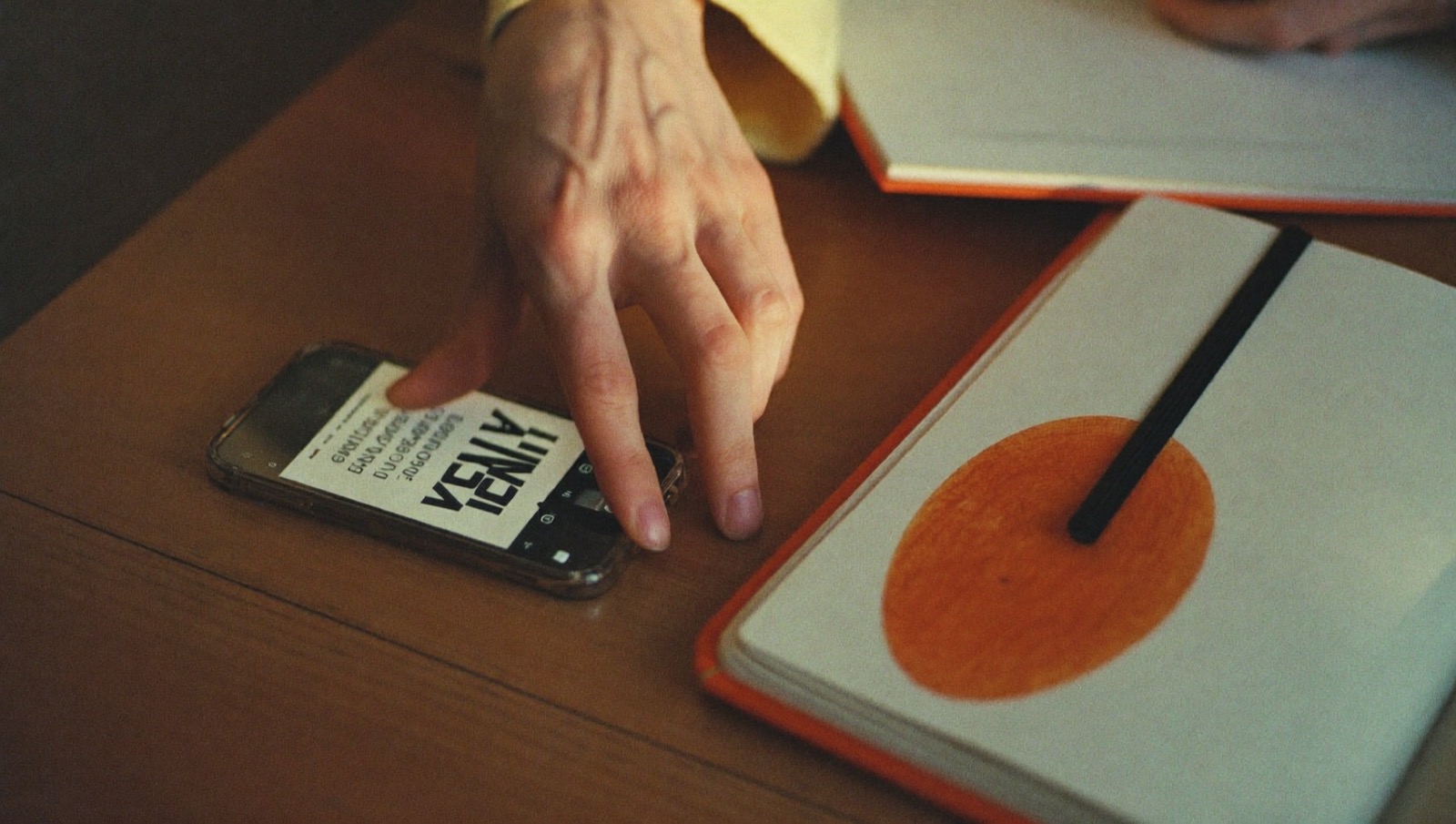 Hand tippt auf ein Smartphone neben einem Notizbuch